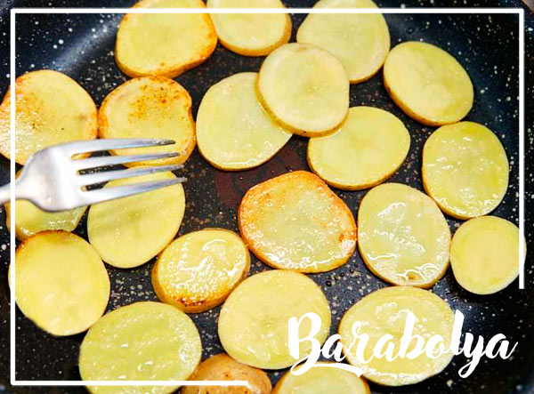 нарежьте картофель тонкими круглыми ломтиками и обжарьте на сковороде на среднем огне до золотистой корочки